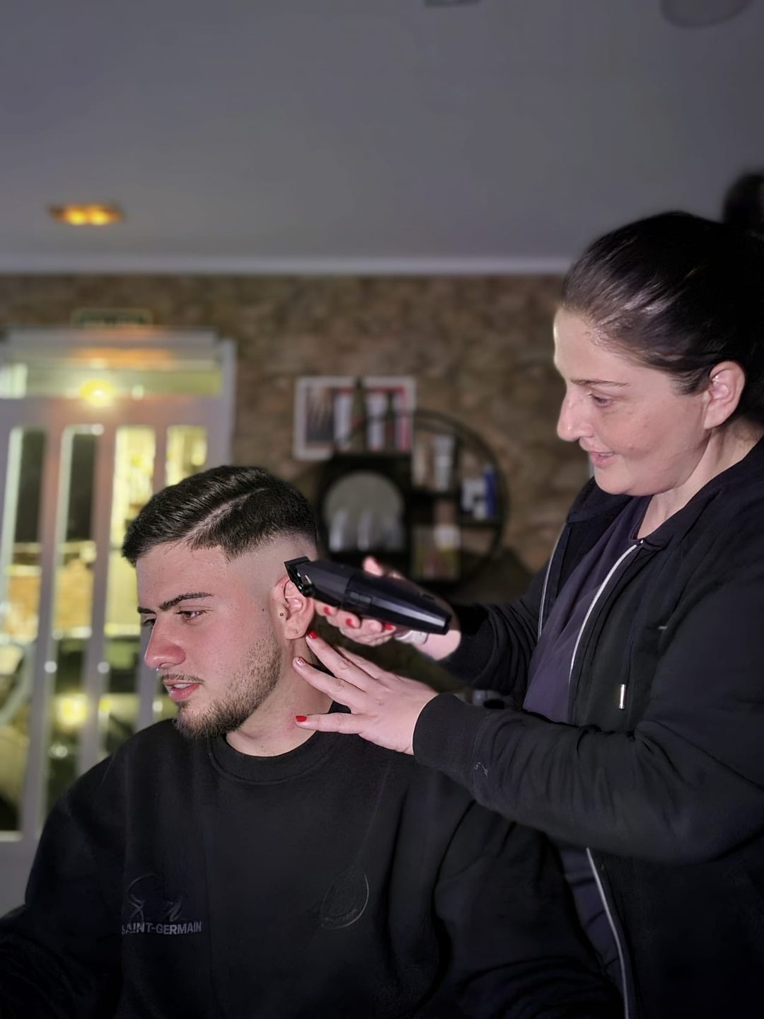 Vanessa cortando el pelo a un cliente en su salón de Ondara